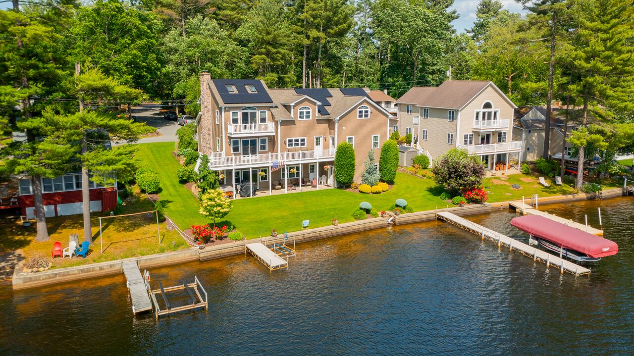 Aerial view of a New England lakefront home with an all-black Rooftop Power solar installation